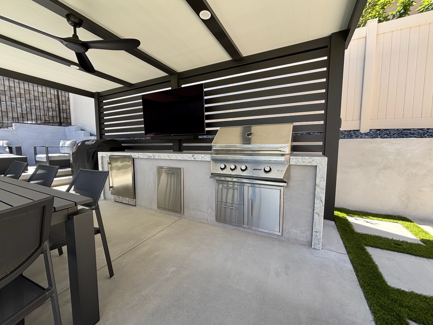 Louvered outdoor kitchen with grill and TV in Lafayette by Abshire Brothers Lawn & Landscape