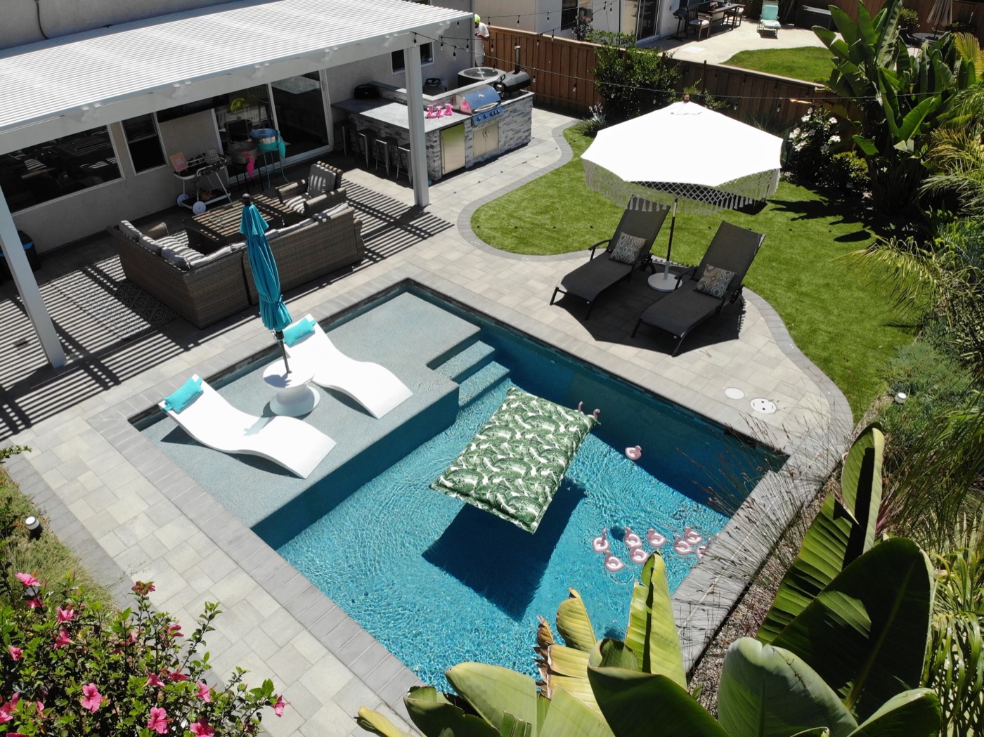 Resort pool with in-water loungers and an outdoor kitchen in Crowley by Abshire Brothers Lawn & Landscape