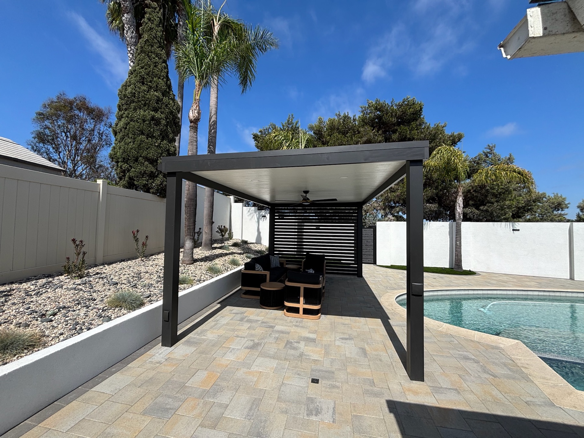 Louvered pergola and poolside pavers, designed and built by Abshire Brothers Lawn & Landscape in Scott, Acadiana