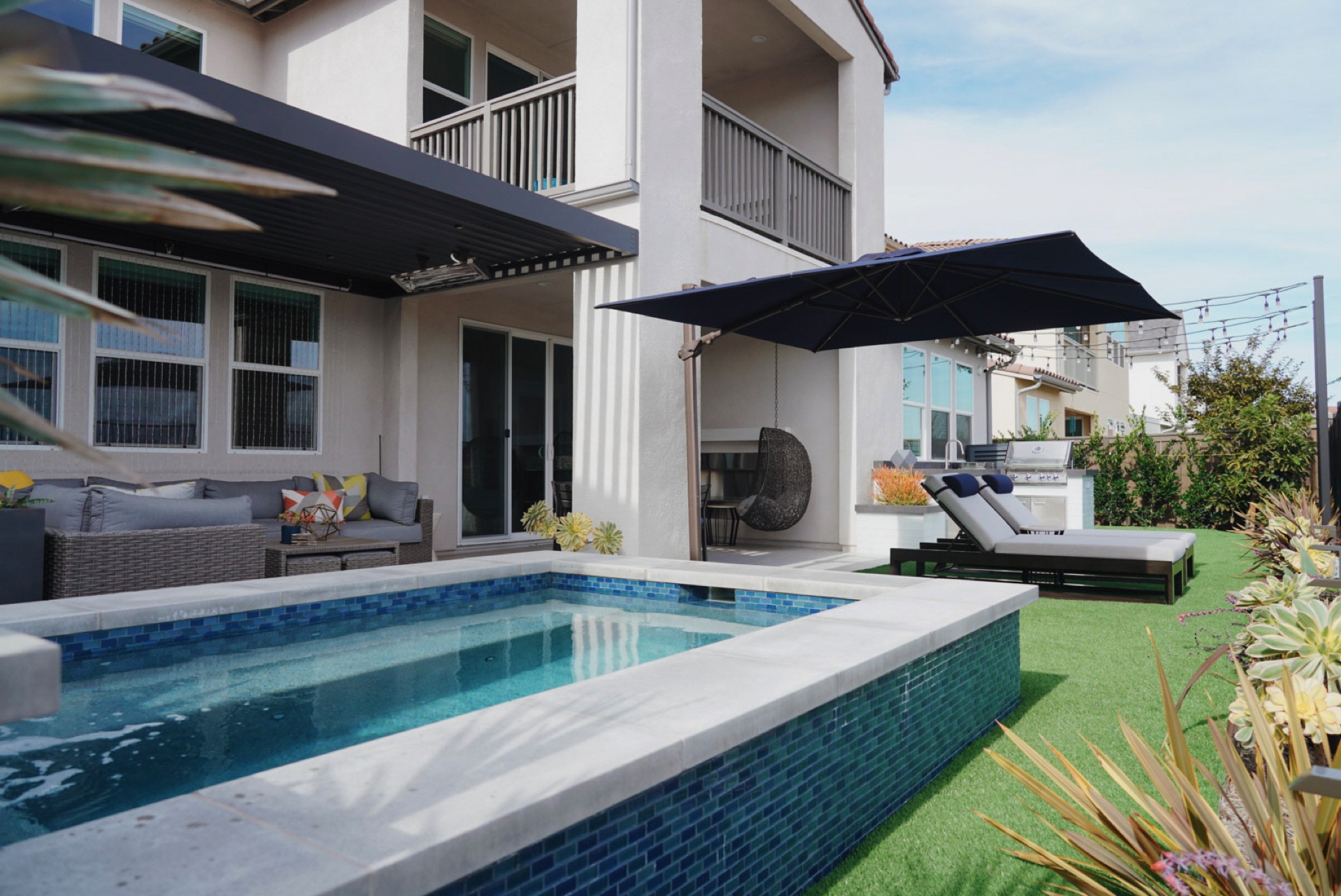 Blue-tile pool with cantilever shade, designed and built by Abshire Brothers Lawn & Landscape in Broussard, Acadiana