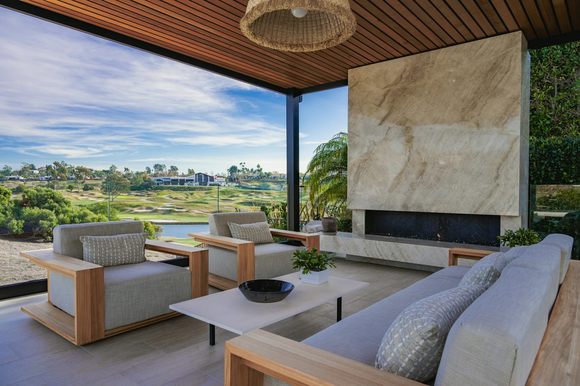 Covered outdoor room with the quartzite fireplace and sectional overlooking the golf course
