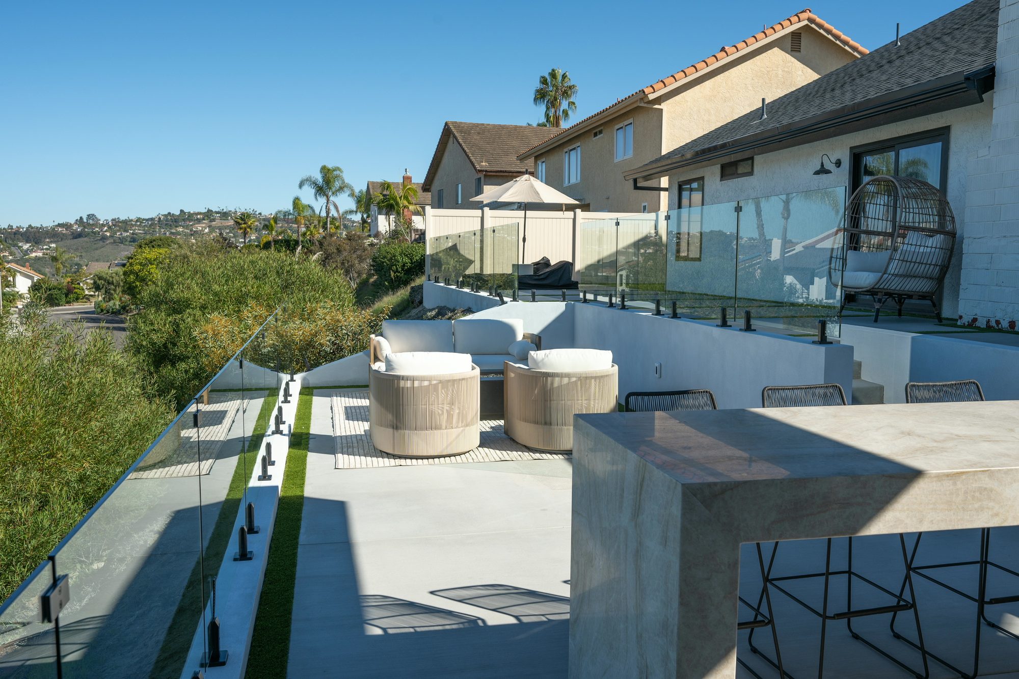 After: the finished multi-level yard with the floating quartzite bar, glass railings and ocean view