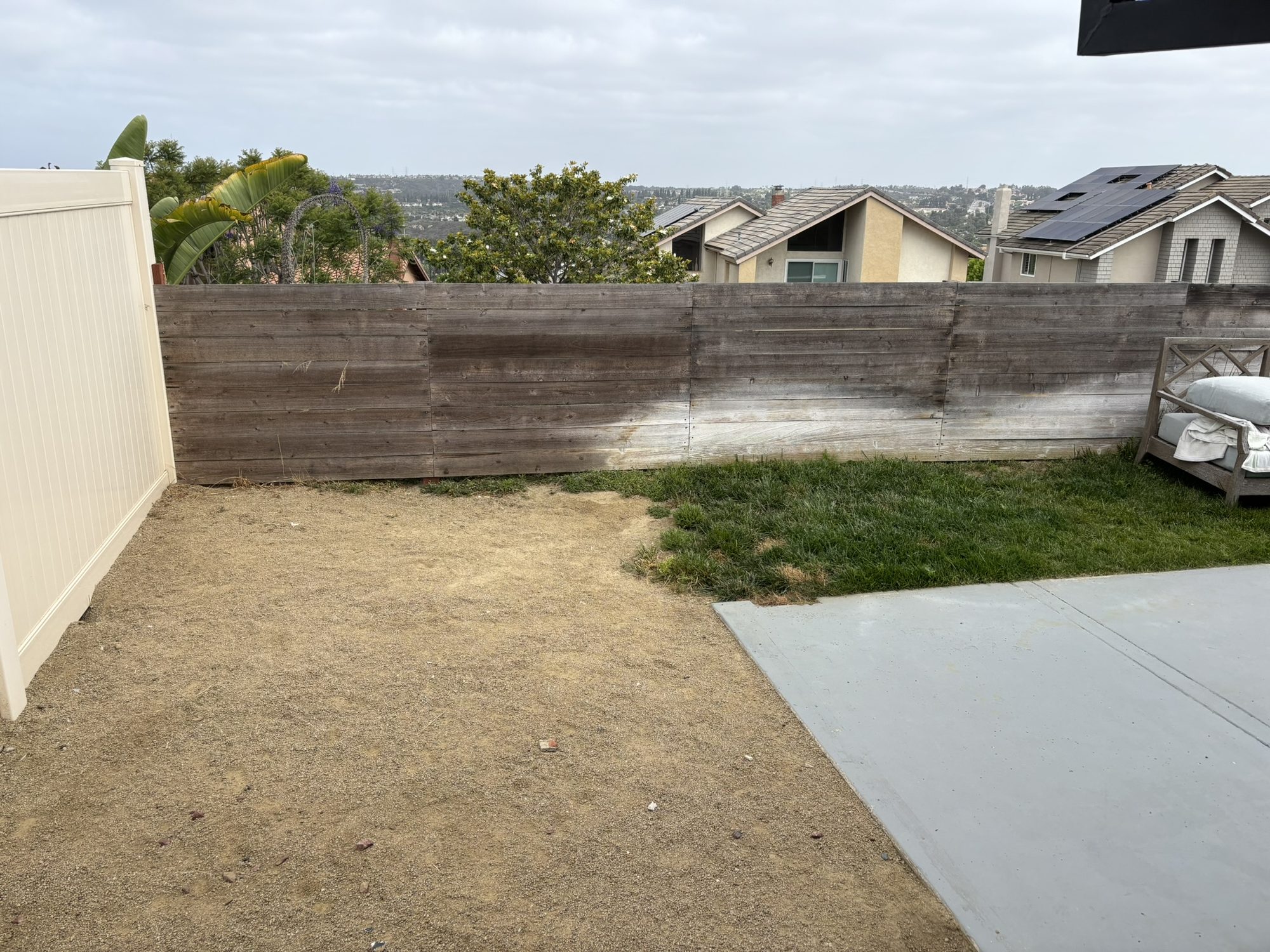Before: the bare dirt Jacka backyard with an old wood retaining wall and vinyl fencing