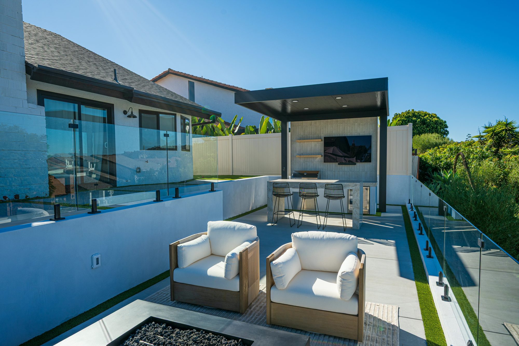 Fire table on the terrace behind frameless glass railings and the ocean view