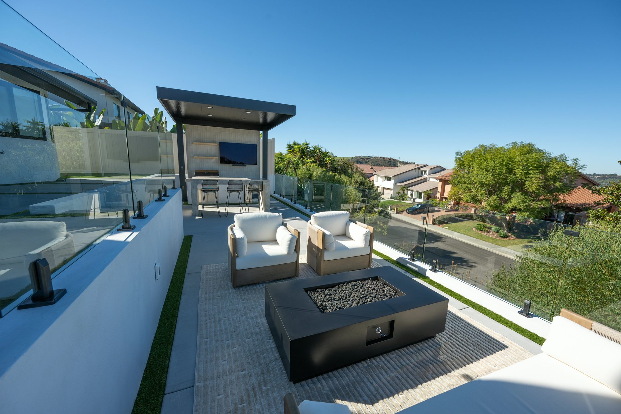 Multi-level Lafayette backyard with a fire-pit lounge, frameless glass railings and an outdoor kitchen framing the ocean view