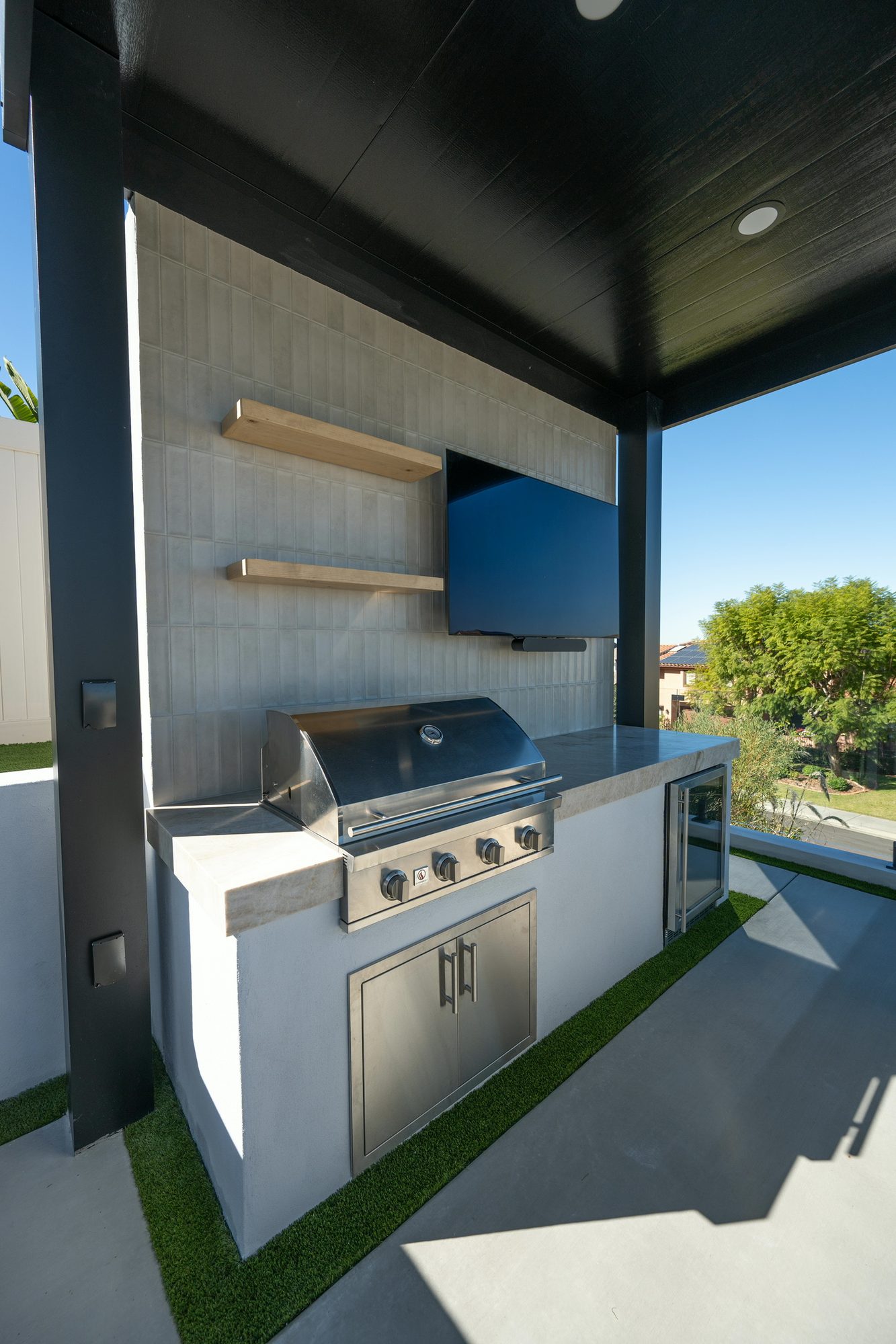 Outdoor kitchen with floating shelves, grill and storage drawers