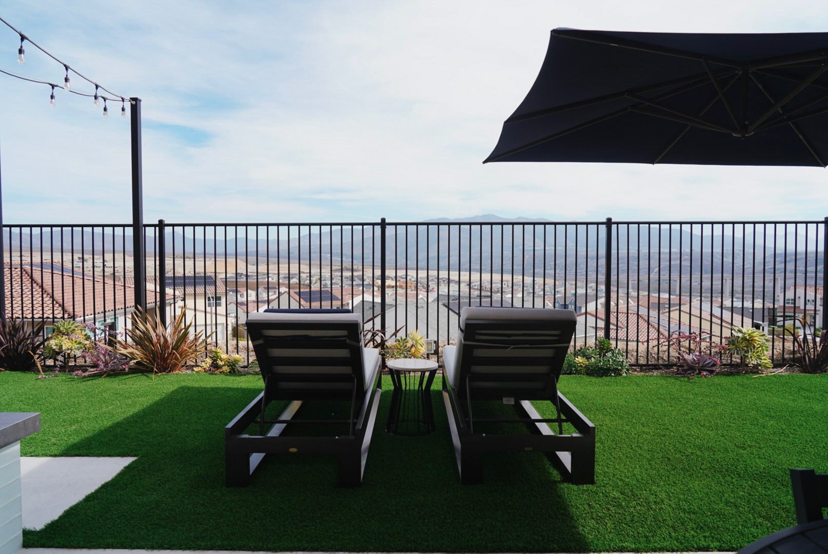 Loungers under a shade sail on the upper turf level with the valley beyond