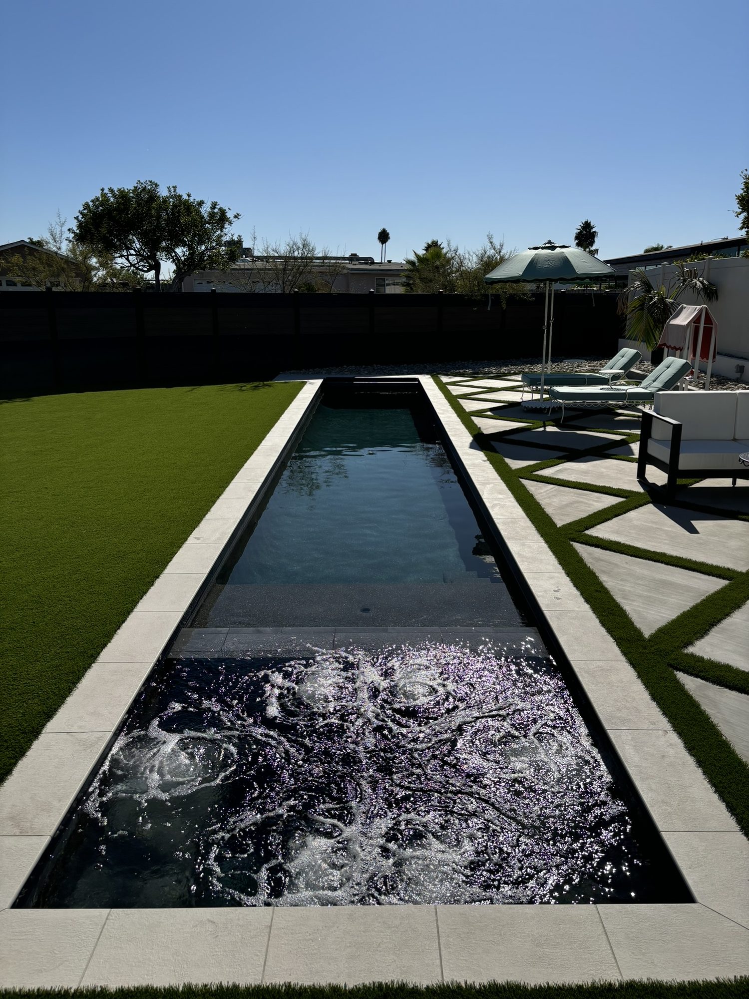 Wide view of the pool, fireplace and loungers with the spa in the foreground