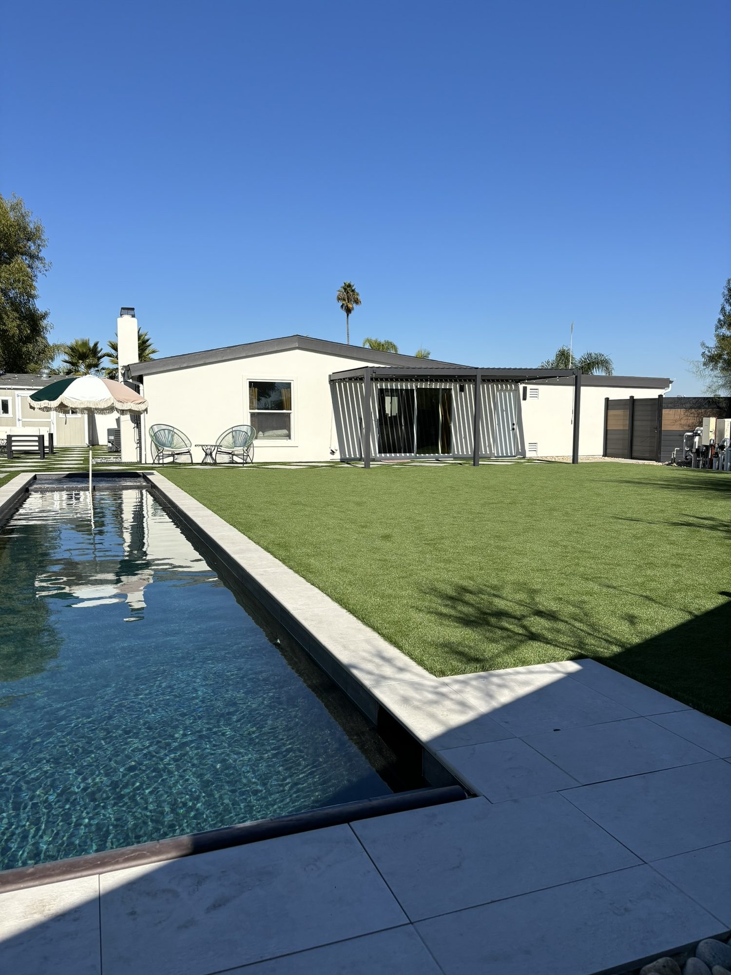 Pool, spa and turf lawn in front of the single-story home