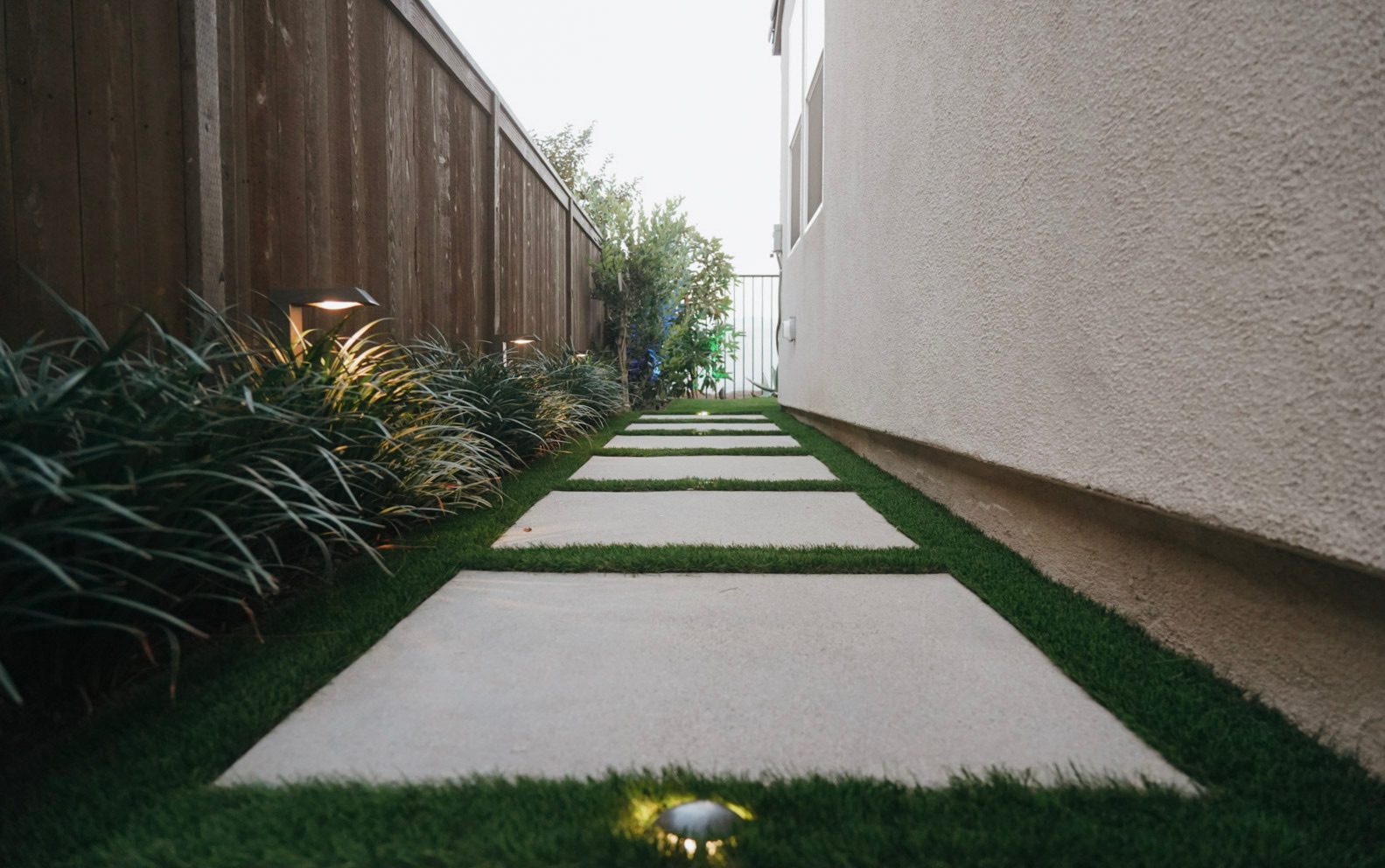 Side yard with artificial turf and top-cast concrete stepping stones