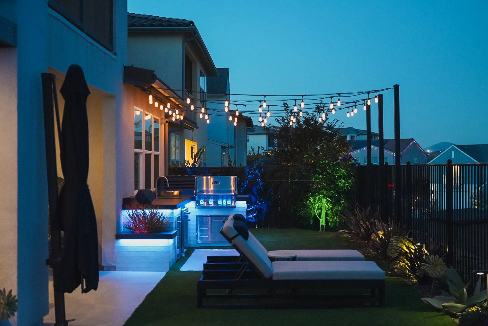 Concealed color-changing LED lighting washing the Kuzma stucco walls at dusk, with string lights above the spool