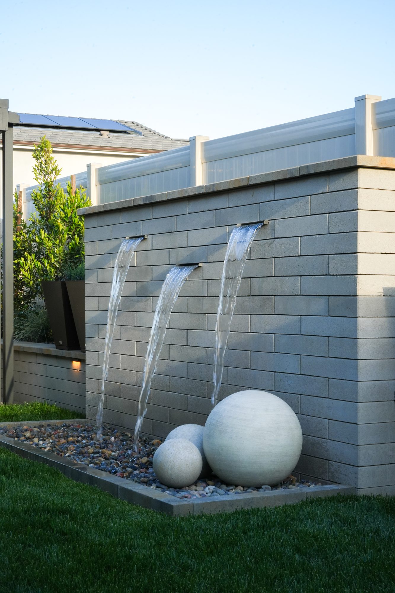 Water feature scuppers pouring past a stone sphere into the riverbed